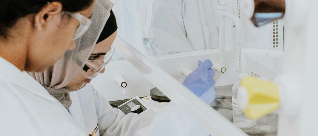 Two students conduct an experiment under a chemistry lab hood