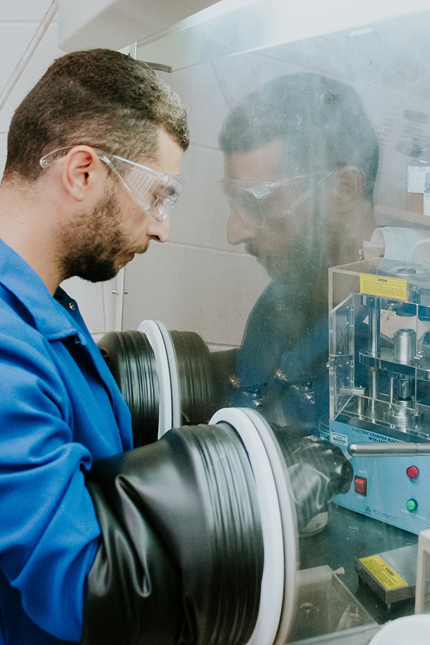 A chemistry student works behind a glass partition