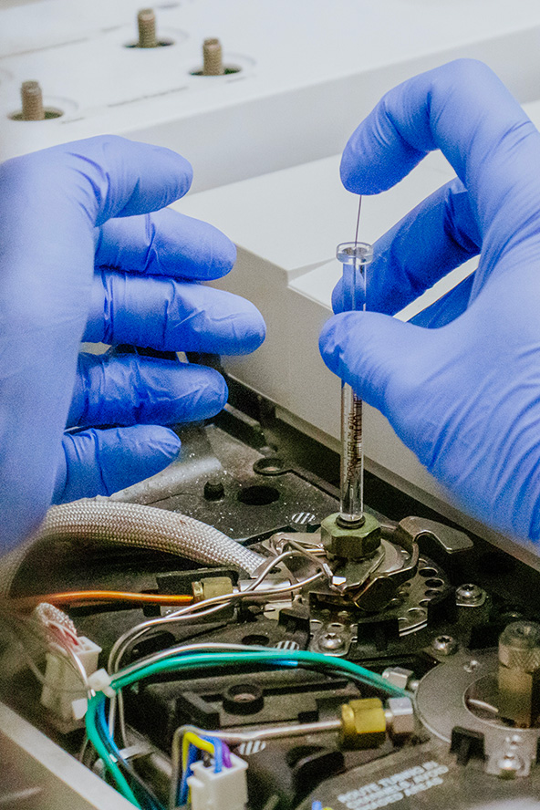 A pair of gloved hands works on mechanical equipment