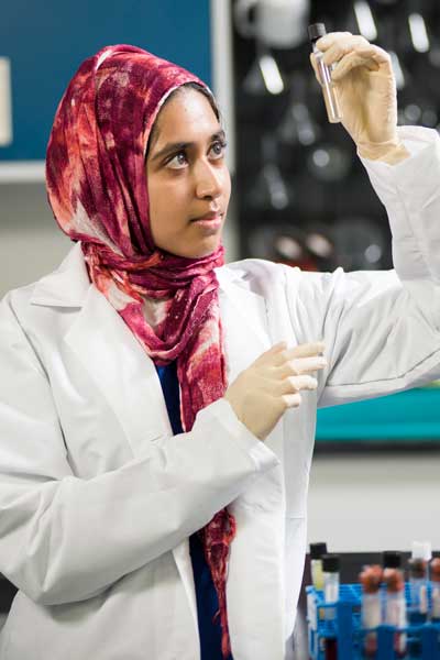 a student in a lab examining a substance in a test tube